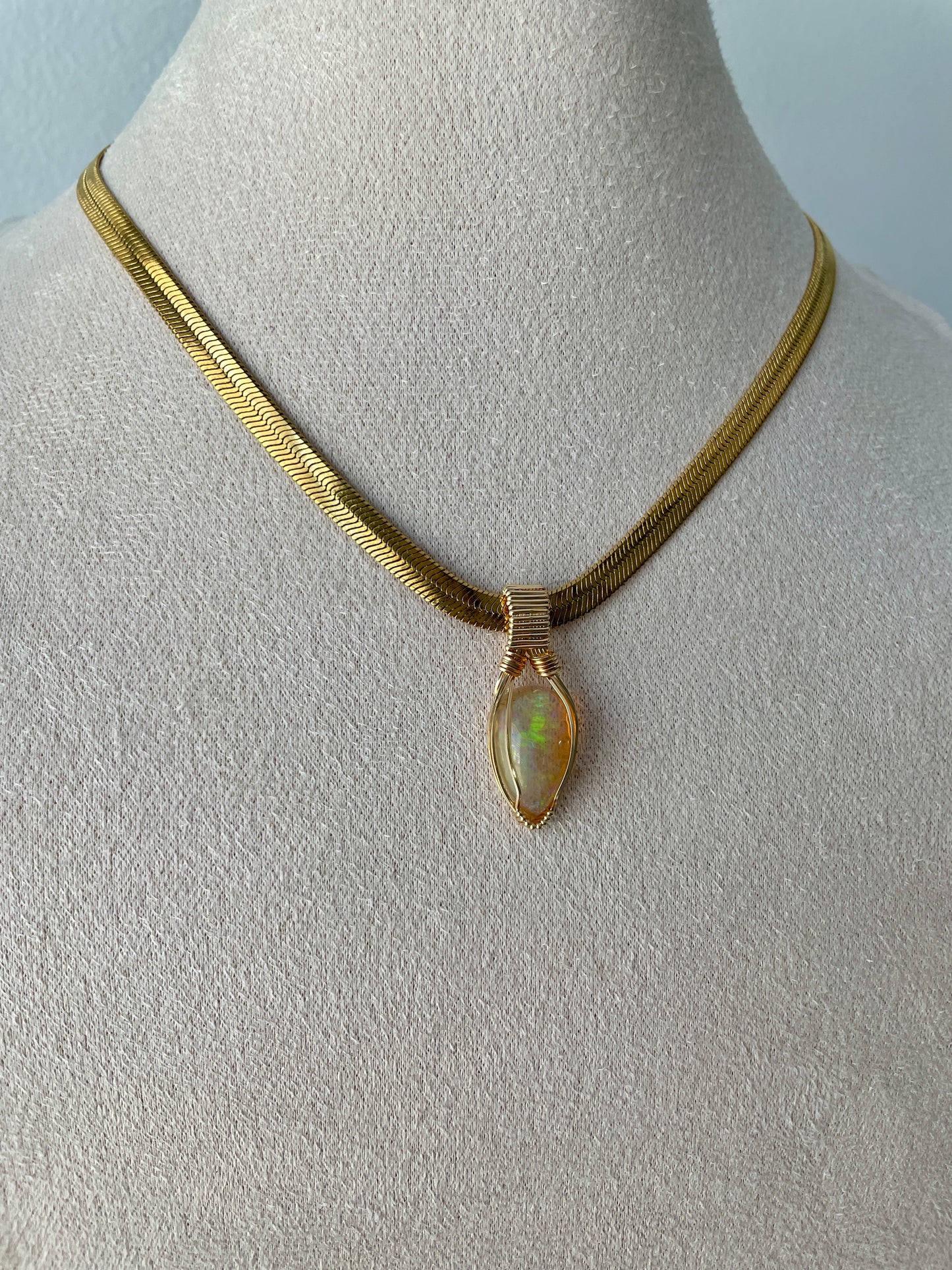 Elegant Ethiopian opal pendant with vibrant rainbow fire, wrapped in 14k gold filled wire and hanging from a 16-inch vermeil gold snake chain.